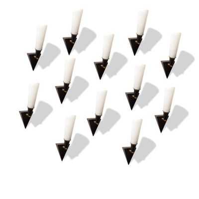 six bougies blanches sont disposées en triangle sur une surface blanche