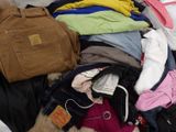 a pile of clothes that is sitting on a bed