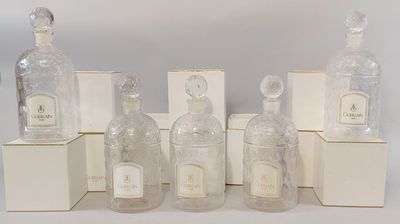 six flacons de parfum sont alignés sur une surface blanche