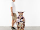 un homme passant devant un grand vase posé par terre