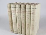 six vieux livres empilés les uns sur les autres sur une surface blanche