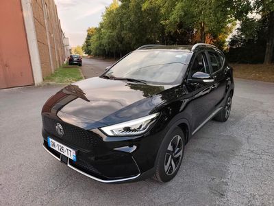 une voiture noire garée dans un parking à côté d'un bâtiment