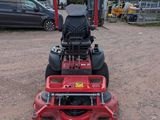 a red lawn mower parked in a parking lot next to a parking lot