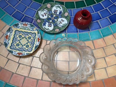 trois assiettes et une bougie posées sur une table en mosaïque