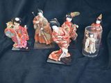 five figurines of asian women in kimono robes are displayed on a black background