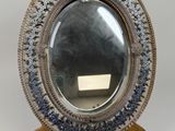 un miroir ancien, argenté et bleu, posé sur un pied avec une base en bois