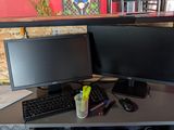 a desk with two monitors and a keyboard on it