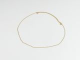 un bracelet en chaîne dorée orné d'une petite breloque en forme d'étoile sur un fond blanc