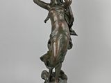 an antique bronze statue of a woman holding a bird in her hand