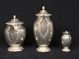 three silver urns and a vase on a black background