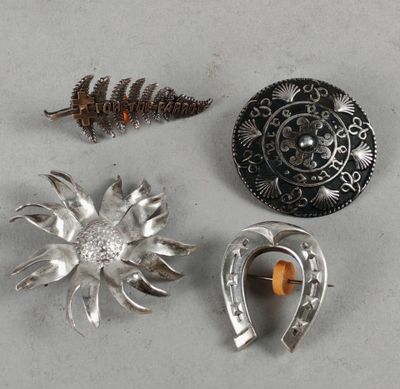 three silver brooches and a silver broochle on a table