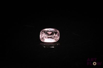 a close up of a pink diamond on a black surface
