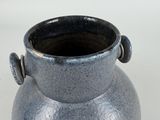 a blue vase with a black handle on a white surface