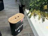 une poubelle noire posée par terre près d'une fenêtre