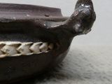 un petit bol marron muni d'une anse, posé sur une table