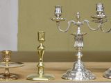 four silver candlesticks on a table next to a mirror