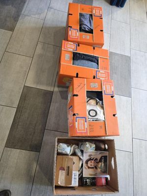 Plusieurs cartons contenant des objets divers sont posés par terre dans une pièce.