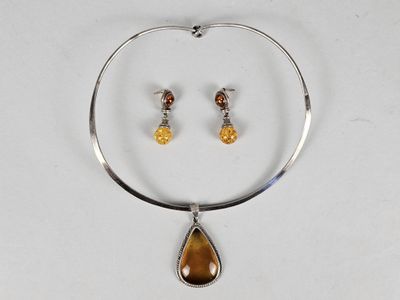 a close up of a necklace and earrings on a white surface
