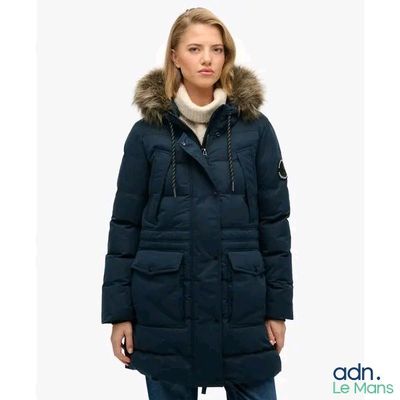 a woman wearing a blue parka with a hood and a fur collar
