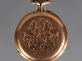 an antique gold pocket watch with a monogrammed initial on it