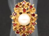 un gros plan d'une bague ornée d'une perle et de grenats