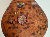 a brown vase with flowers on it sitting on a table