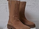 pair of brown boots sitting on top of a box on top of a washing machine