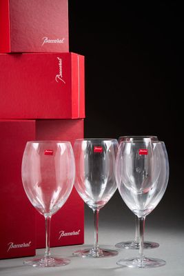 trois verres à vin vides devant une boîte rouge ornée d'un ruban rouge