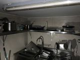 une cuisine équipée d'un évier, d'une cuisinière et d'autres éléments posés sur le plan de travail