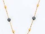 a black and gold beaded necklace on a gold chain
