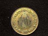 a close up of a gold coin with a monogram on it