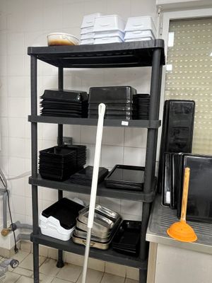 une étagère noire dans la cuisine, avec une serpillière à côté