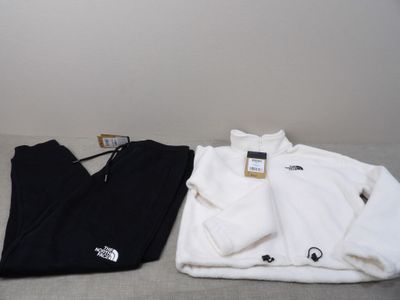 deux paires de vêtements blancs et noirs posées sur un lit