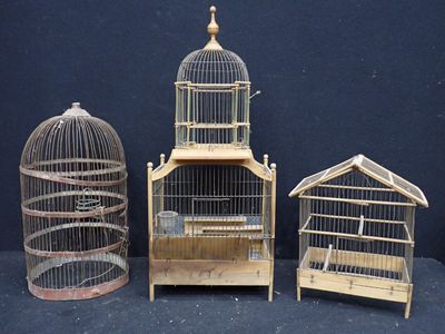 trois petites cages à oiseaux en bois posées les unes à côté des autres sur une surface noire