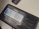 a digital clock on a table next to a cell phone