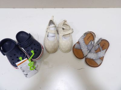 Plusieurs paires de chaussures pour bébé sont alignées sur une table blanche