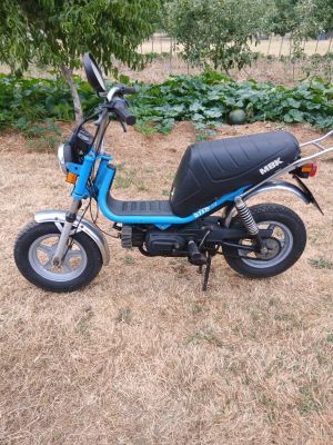 une photo d'un petit scooter garé dans un champ