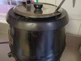 une casserole noire posée sur une cuisinière, avec une cuillère à l'intérieur