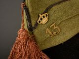 a green hat with a brown tassel on it
