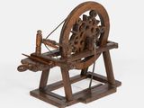 un rouet en bois exposé sur un fond blanc