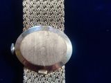an image of a close up of a wrist watch on a blue surface