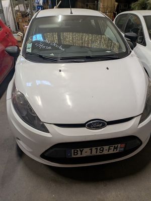 a white car parked in a garage next to a red car