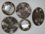 six silver plates are arranged in a circle on a white surface