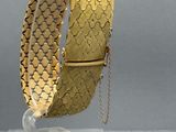 an image of a gold bracelet with a chain hanging from it