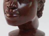 sculpture marron représentant la tête d'une femme, posée sur un socle en bois