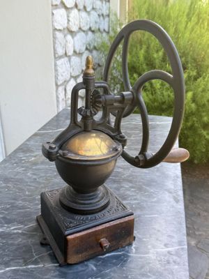 un petit moulin à café ancien posé sur une table en marbre