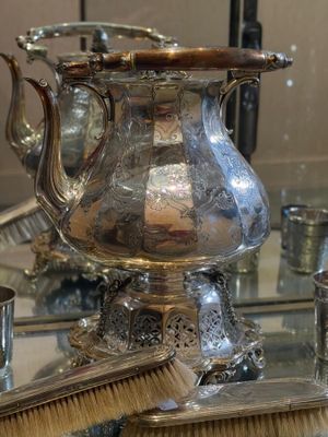 a silver tea pot sitting on top of a table next to a mirror