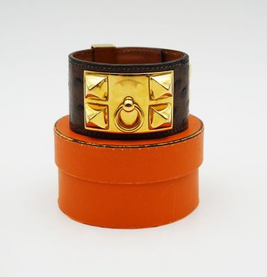 two orange and black leather bracelets with a gold buckle
