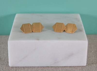 un gros plan sur une paire de boucles d'oreilles en or posées sur un bloc de marbre