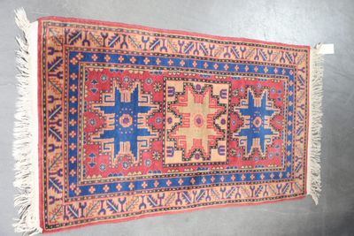 an old rug hanging on a wall with a blue and red design